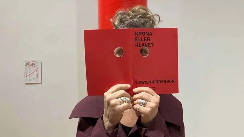 Bild på en kvinna  som håller en bok framför ansiktet för utställningen krona eller klave