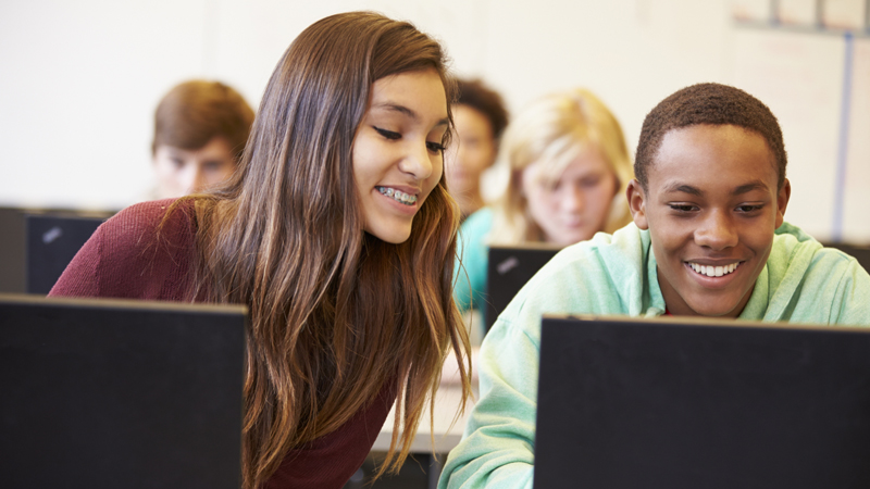 En tjej och kille sitter framför datorer