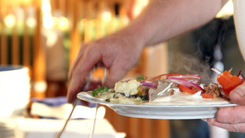 Någon fyller på mat från en buffé på sin tallrik