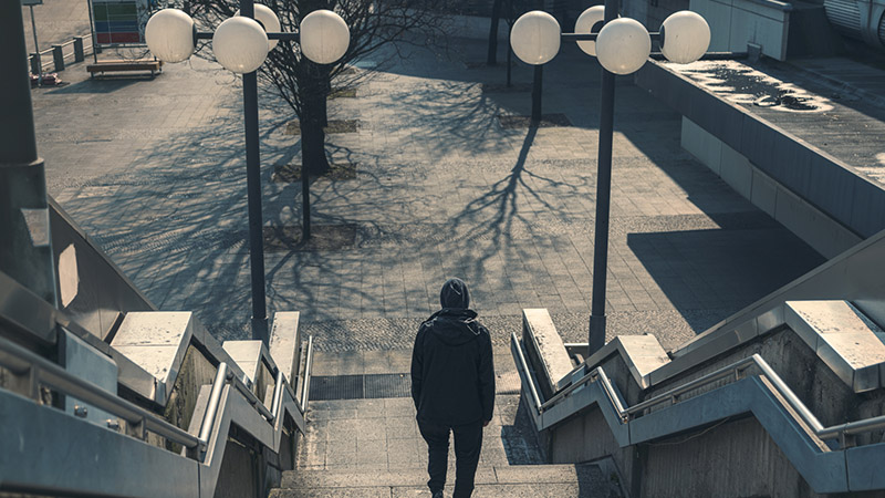 Ungdom i luva går nedför trappa med ryggen mot kameran