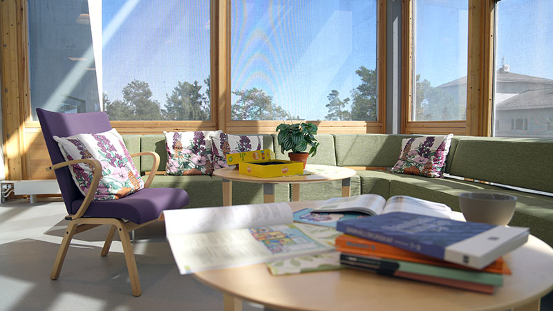 En grön soffa och en lila fåtölj i ett uppehållsrum med stora fönster.