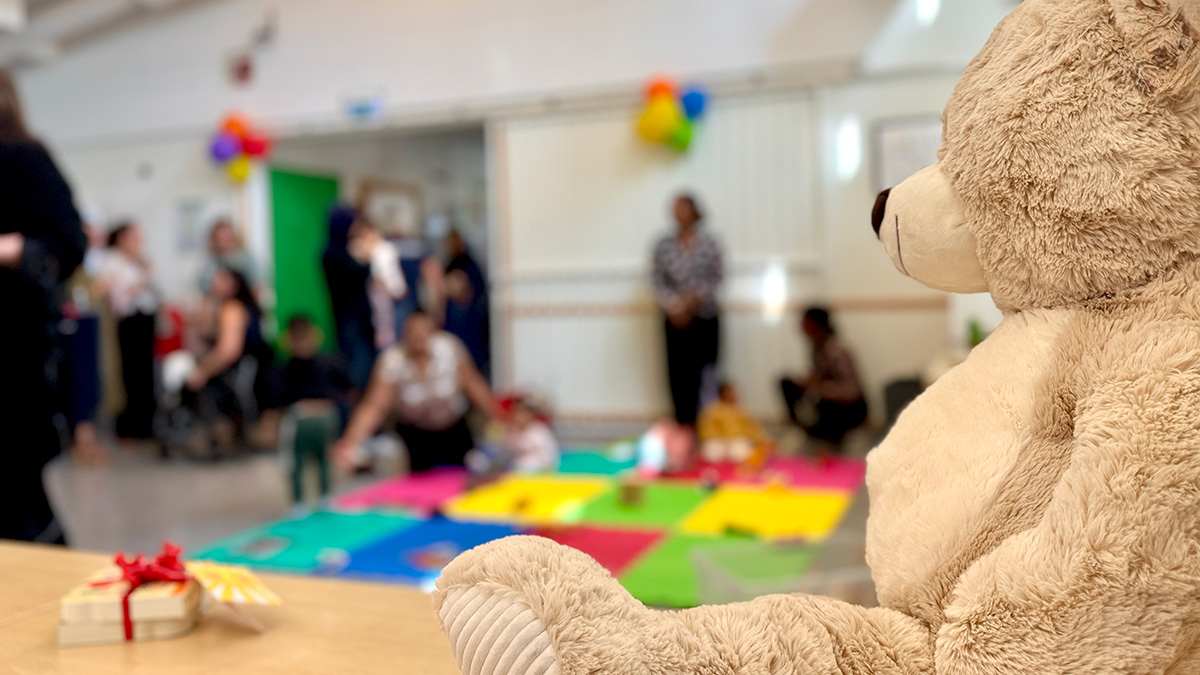 Nallebjörn i förgrunden, i bakgrunden barn och vuxna.