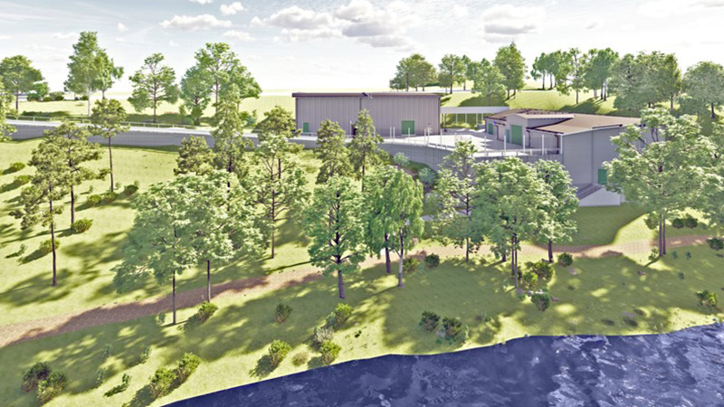 Ett avloppsreningsverk liggandes vid strandkanten omgiven av träd. 