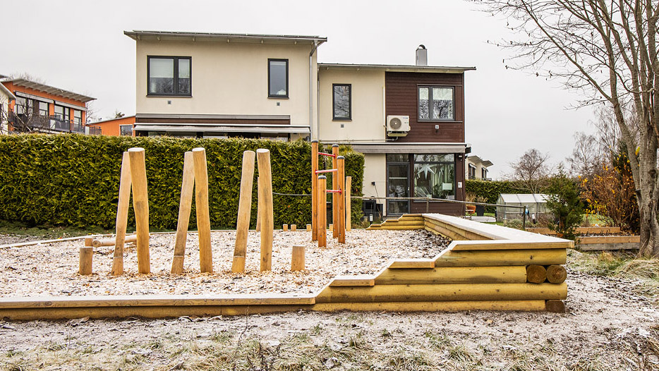 Balanslek på en lekplats med ett hus bakom