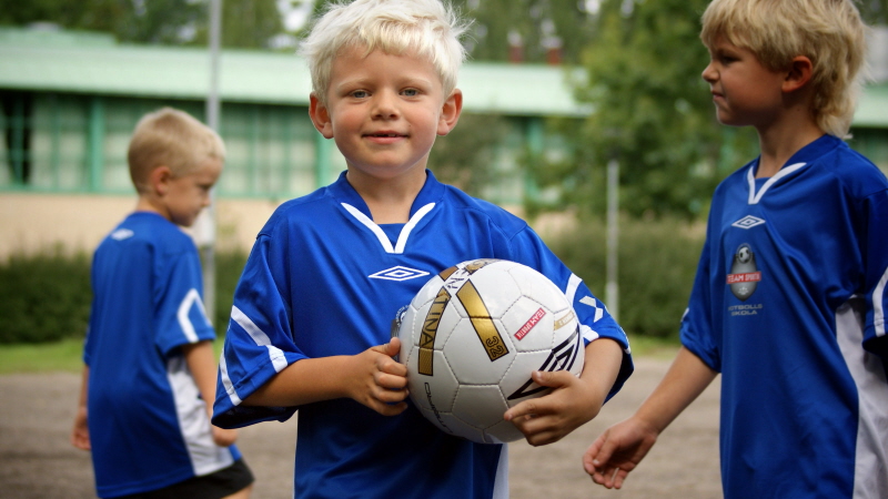 Pojke på fotbollsskola håller i en boll