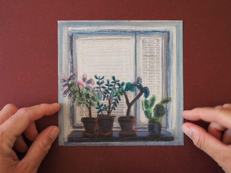 två händer håller i en teckning av ett fönster