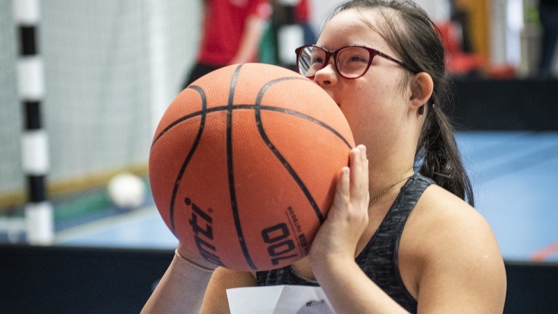 En tjej står på basketplanen med en basketboll i händerna.
