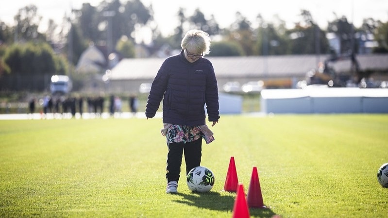 En tjej spelar fotboll på en fotbollsplan.